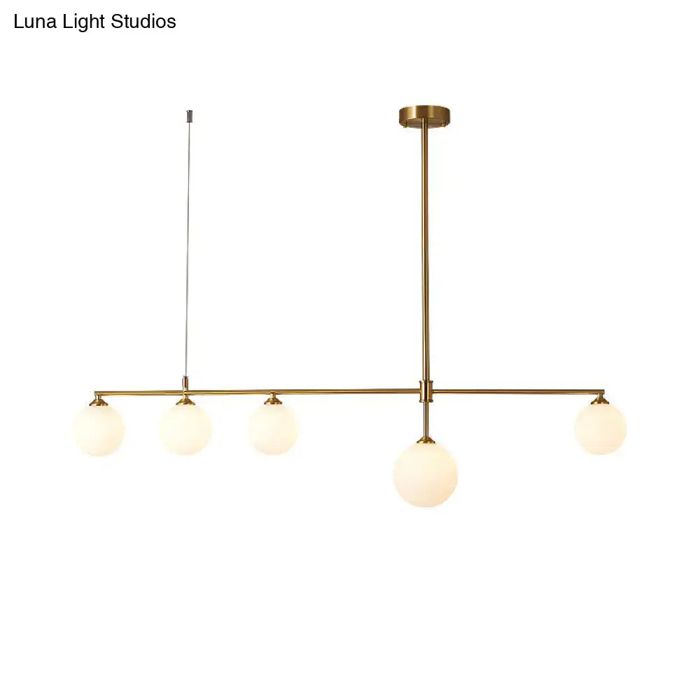 Brass-finished DecorBites gold opaline glass pendant ceiling light with five frosted globe shades in linear design