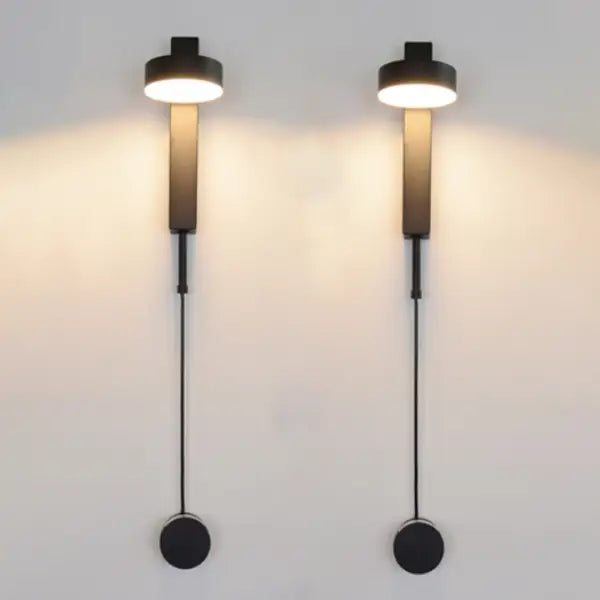 Modern black wall lamps with cylindrical shades and slender stems featuring a dimmer switch for adjustable lighting