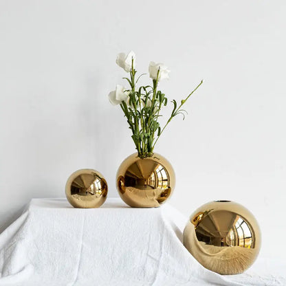 Decorbites golden ball ceramic vases in shiny gold with varying sizes and one holding white flowers for home decor