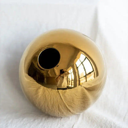 DecorBites™ golden ball ceramic vase with a shiny gold spherical smooth reflective surface for home decor