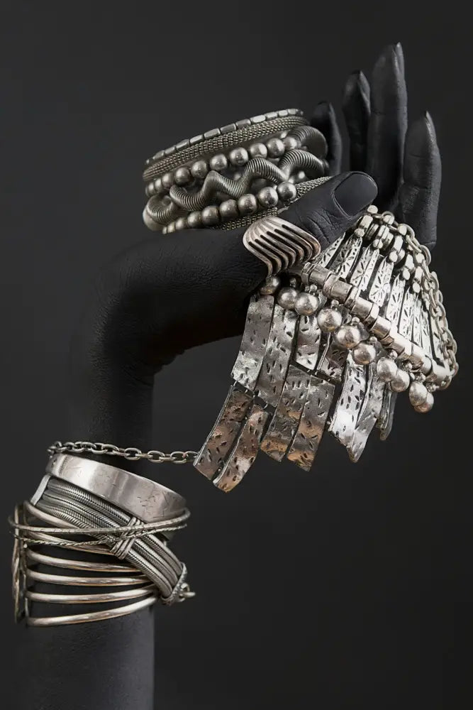A silver fringe bracelet with dangling beads and hammered plates featured in decorbites golden jewelry african woman canvas art