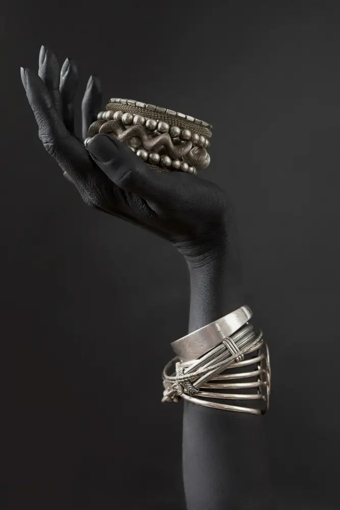 A stack of intricate silver-toned bracelets with textured bands featured in decorbites™ golden jewelry african woman canvas art