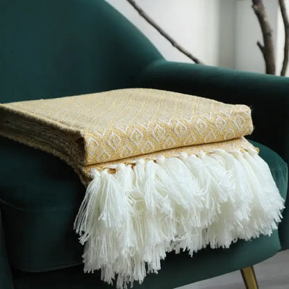 A decorbites golden knitted cream throw blanket with a subtle geometric pattern and white tassels for living room use
