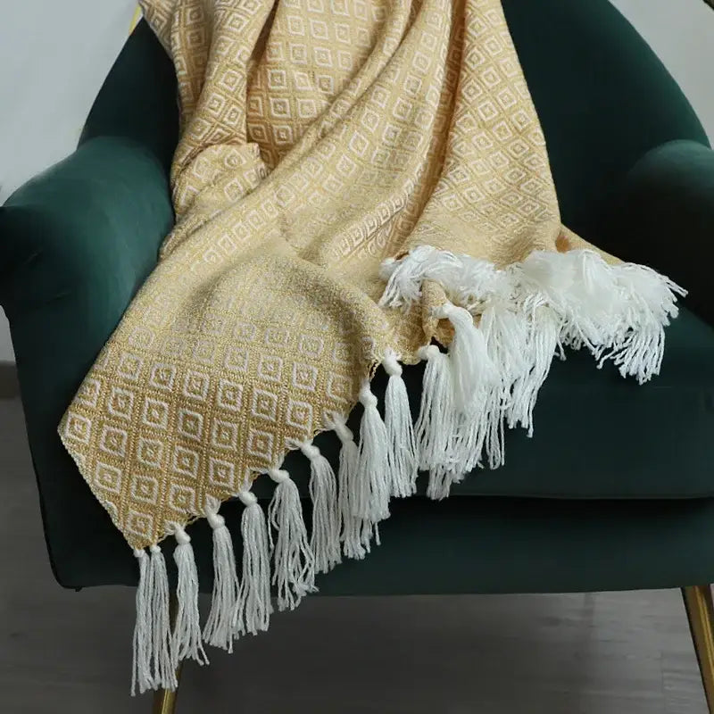A soft decorbites golden knitted blanket in golden yellow with a geometric pattern and white tassels for living room decor