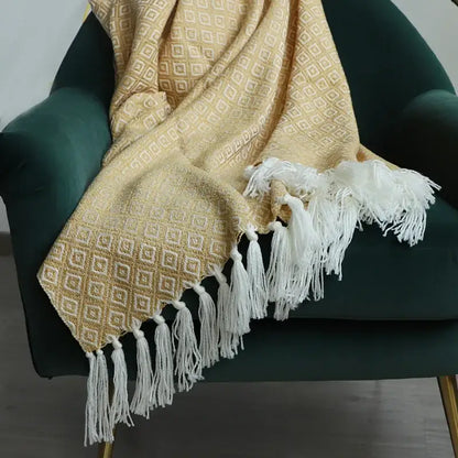 A soft decorbites golden knitted blanket in golden yellow with a geometric pattern and white tassels for living room decor