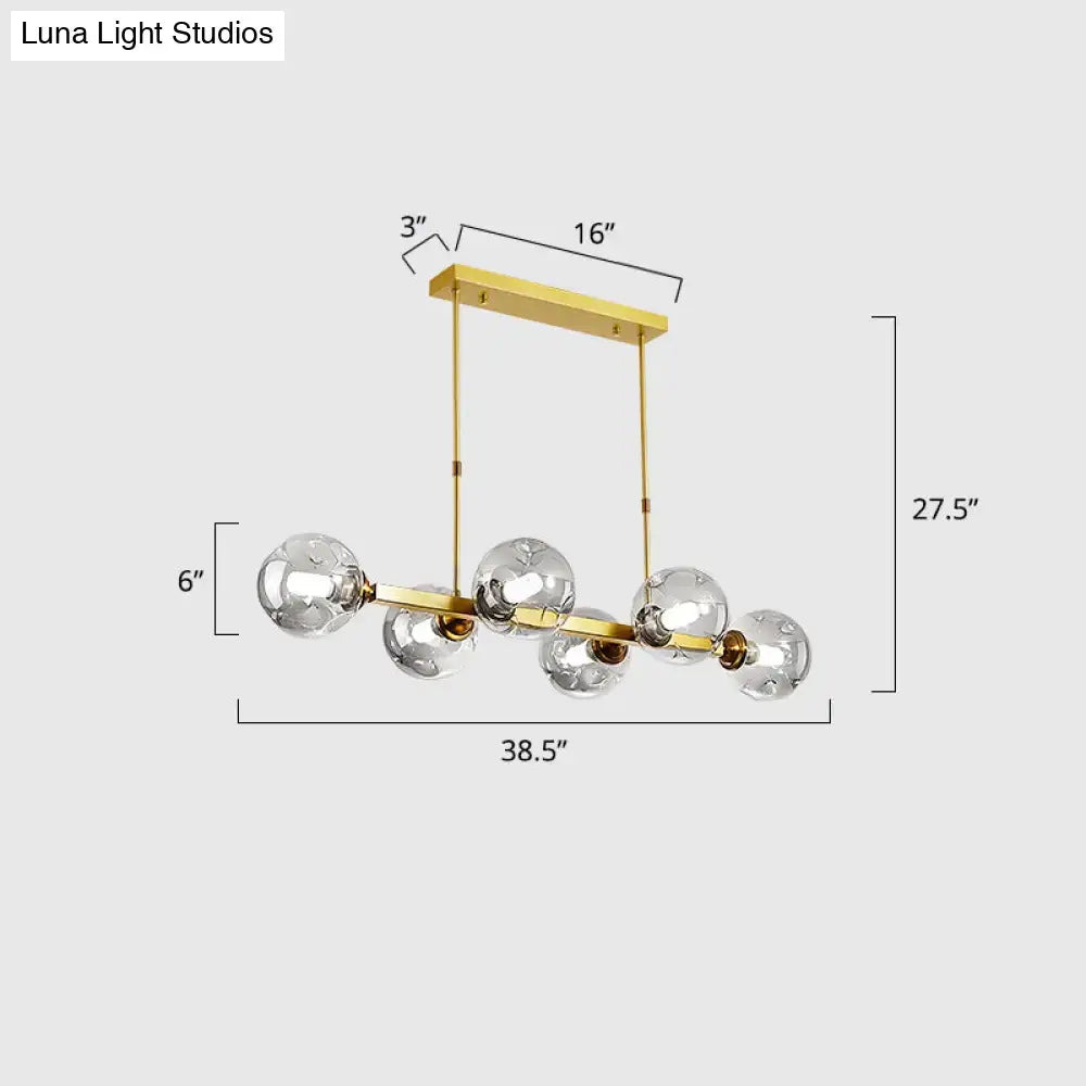 Gold-toned decorbites™ hand-blown dimpled glass island pendant lamp with five clear globe bulbs and rectangular ceiling mount