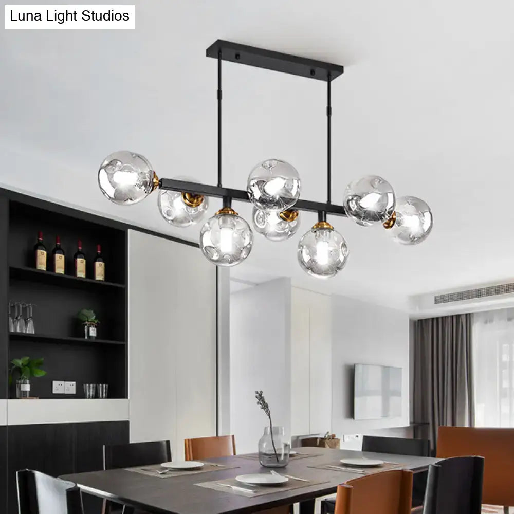 Modern black metal chandelier with gold accents and hand-blown dimpled glass globe bulbs for restaurant lighting