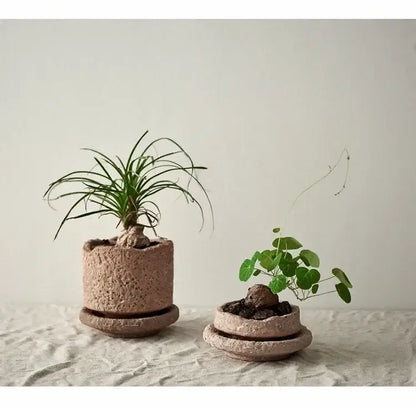 Two earth-toned handcrafted ceramic vases with textured pottery finish and matching saucers for flowers by DecorBites