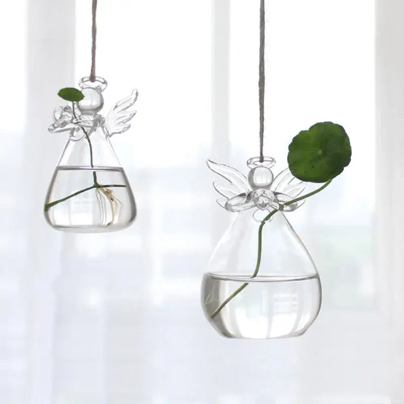 Clear glass angel-shaped hanging planters with delicate wings holding water and a green leaf for home decor by DecorBites™