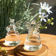 Clear glass DecorBites™ handmade angel glass vase with delicate wings holding white and blue flowers