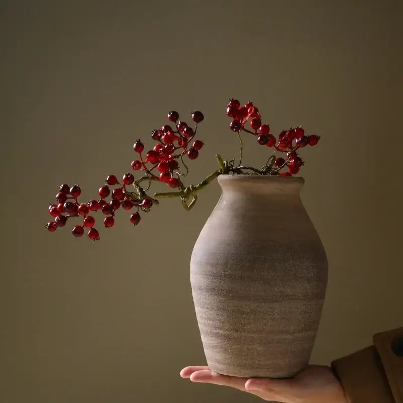 DecorBites™ handmade ceramic vase in rustic terracotta with horizontal ridges holding vibrant red berries home decoration