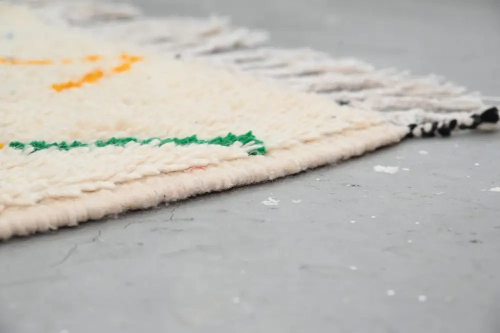 Cream-colored handmade moroccan azilal rug with colorful geometric patterns and fringed edges 222 x 139 cm