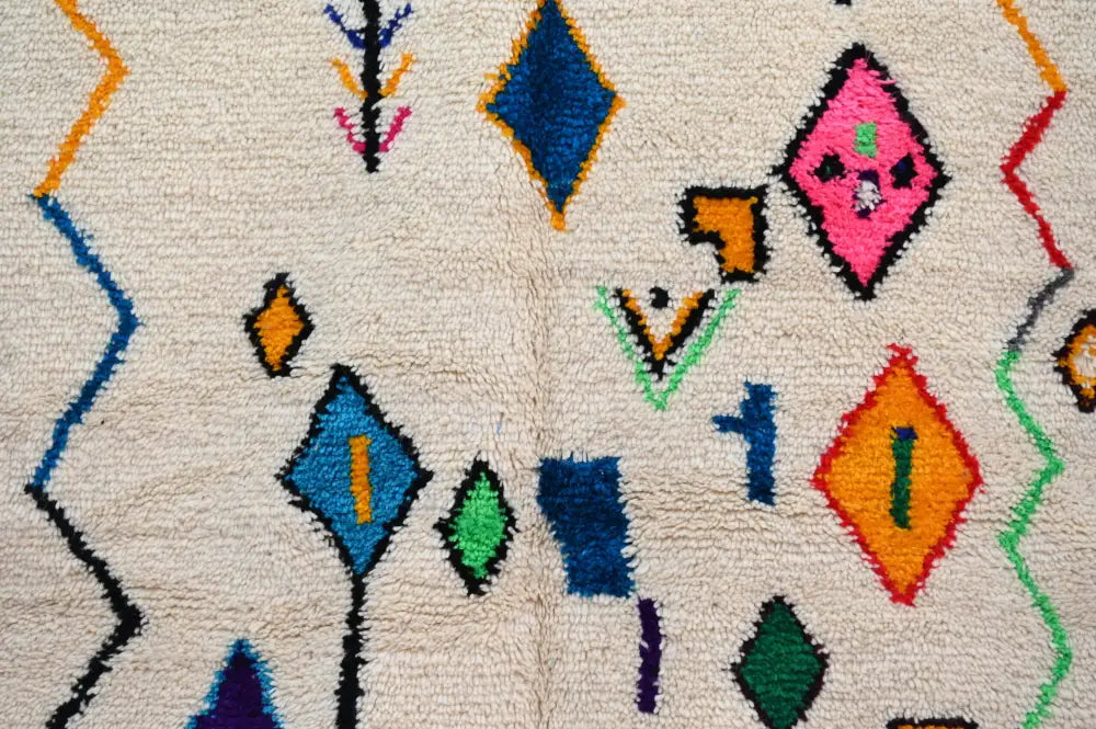 A cream-colored handmade moroccan azilal rug with vibrant blue pink orange green and purple geometric patterns 222 x 139 cm