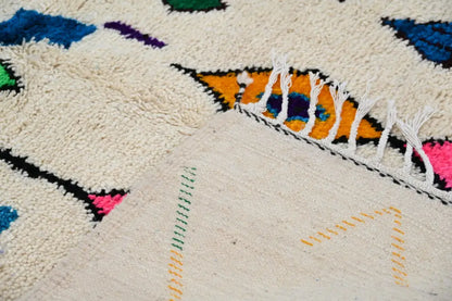 Cream-colored handmade moroccan azilal rug with vibrant geometric patterns and textured woolen surface by DecorBites™