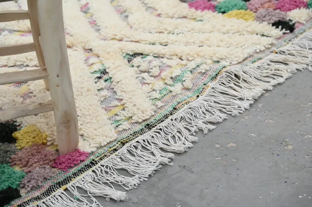 Handmade azilal rug 222x133 with cream base and vibrant floral patterns featuring long white fringe by decorbites