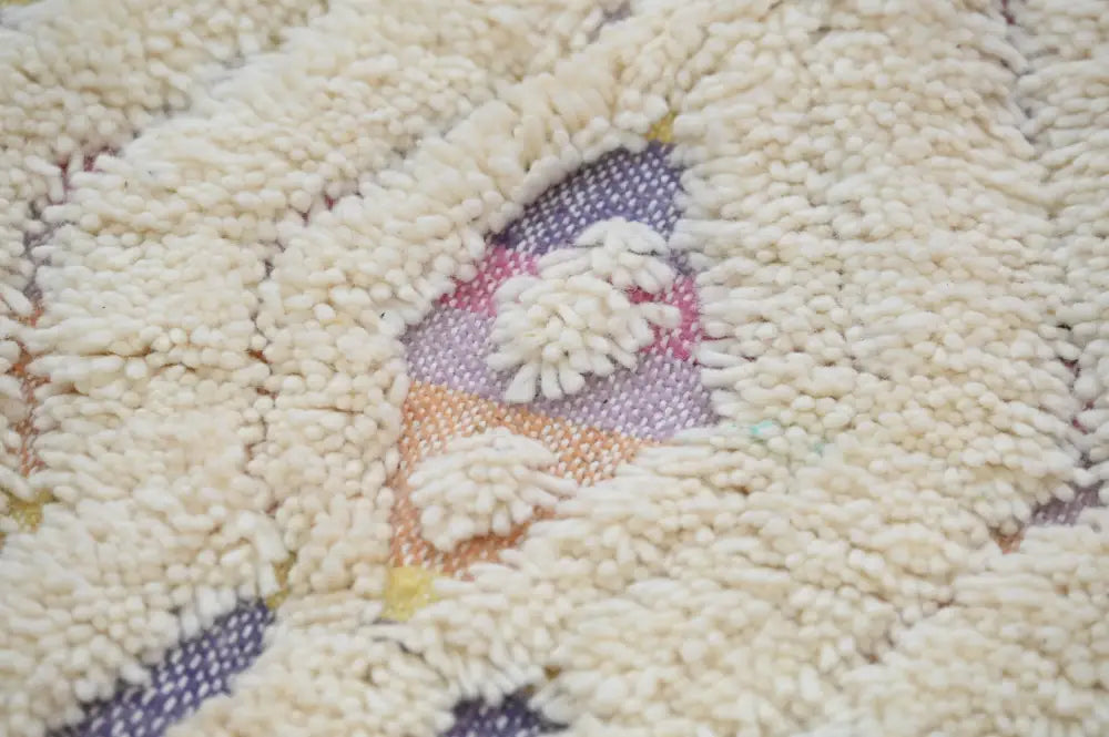 Cream-colored plush handmade Moroccan azilal rug with central pastel pink lavender and orange geometric pattern 223x133 cm