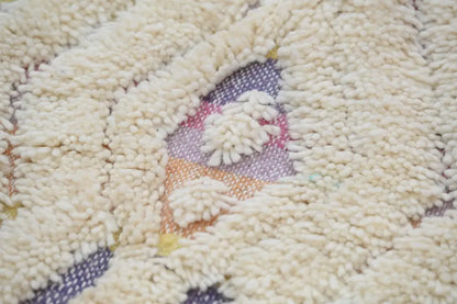 Cream-colored plush handmade Moroccan azilal rug with central pastel pink lavender and orange geometric pattern 223x133 cm