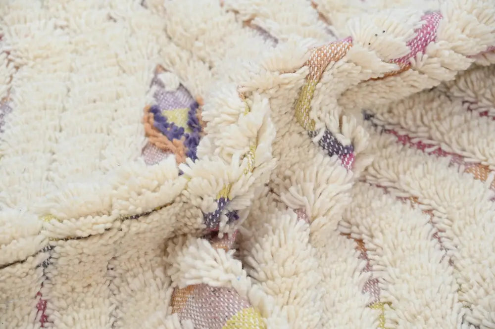 Cream-colored plush traditional azilal rug with intricate woven patterns in muted purples pinks and earthy tones handcrafted by decorbites