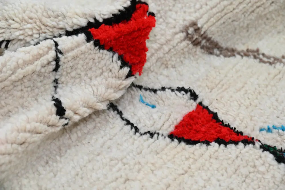 Cream-colored moroccan handmade azilal rug with bold red black geometric patterns and natural wool material 223x157cm