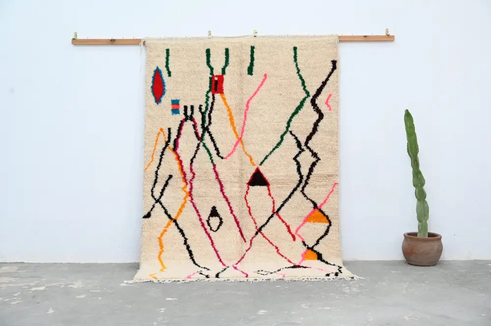 Beige moroccan handmade azilal rug with abstract geometric patterns in red green black orange and pink by DecorBites