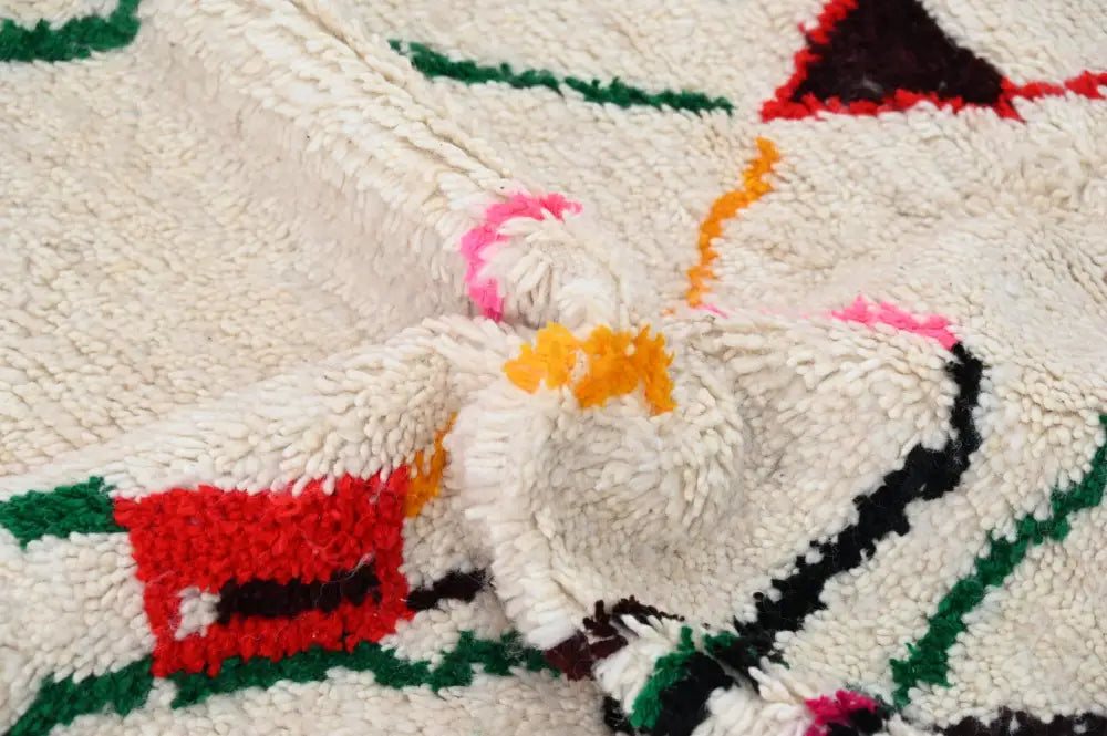 Cream-colored plush wool azilal rug with bold red green black and pink geometric patterns moroccan handmade craftsmanship