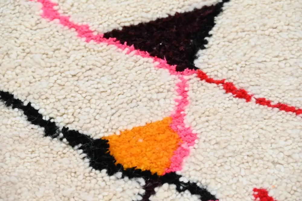 Cream-colored moroccan handmade azilal rug with bold black pink and orange geometric patterns showcasing moroccan craftsmanship