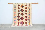 Beige woven decorbites handmade moroccan azilal rug 236x155cm with geometric diamond and arrow patterns in orange red pink and black