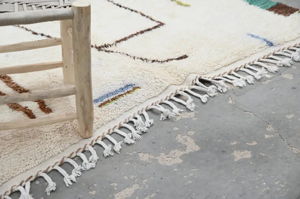 Cream-colored moroccan handmade azilal rug with geometric brown blue and green patterns and white woven fringe 237x146 cm