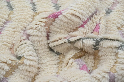 Cream-colored handmade moroccan azilal rug with soft pink and muted gray geometric patterns in plush textured fibers