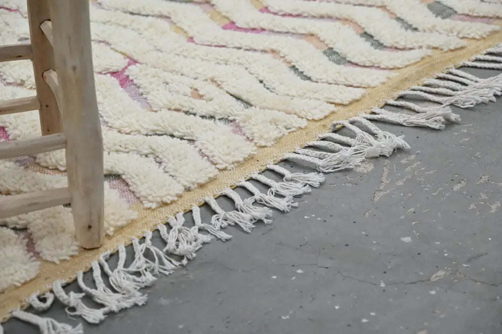 Cream-colored chunky-knitted handmade moroccan azilal rug with pink gray zigzag pattern and long white fringe 238x144cm
