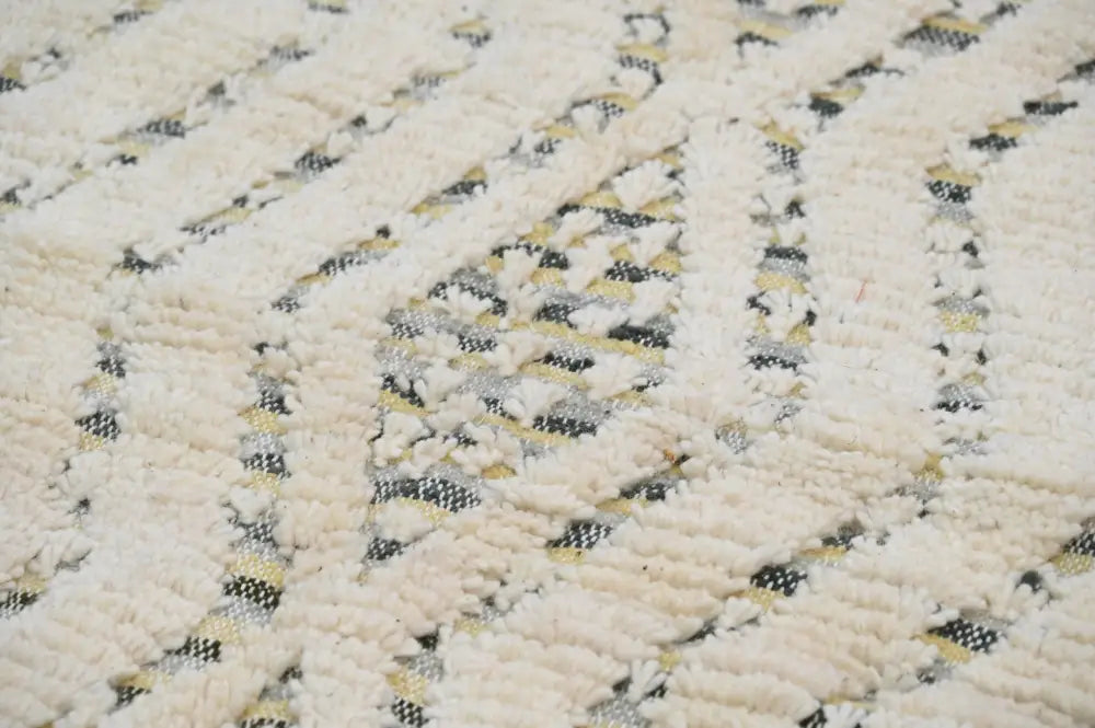 Cream-colored handmade moroccan azilal rug 240x155cm with textured woven pattern featuring black and beige geometric designs