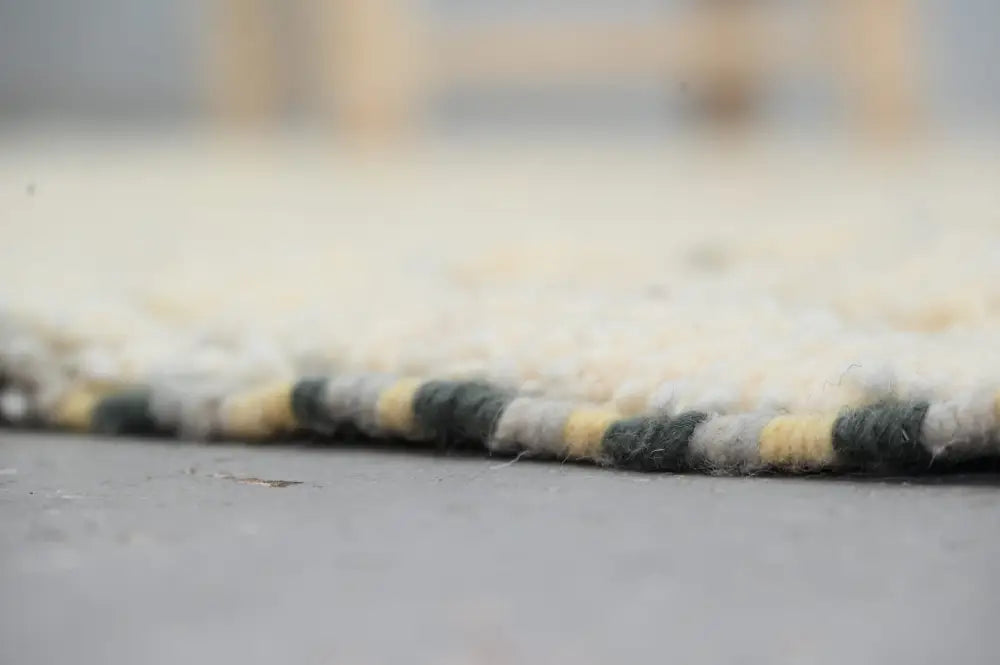 Cream-colored azilal rug 240x155cm with textured woven edge featuring yellow and dark green stripes handmade moroccan azilal