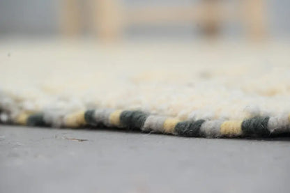 Cream-colored azilal rug 240x155cm with textured woven edge featuring yellow and dark green stripes handmade moroccan azilal