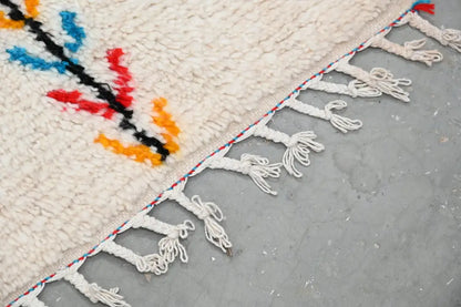 Cream-colored handmade moroccan azilal rug with vibrant red blue orange geometric patterns and white fringe 242x150cm