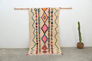 Beige handmade moroccan azilal rug with vibrant pink orange green and blue geometric patterns by DecorBites™ 243x131 cm