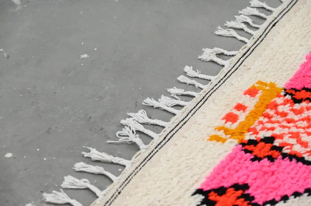 Vibrant handmade moroccan azilal rug with cream base and bold pink orange black geometric patterns 245x141cm