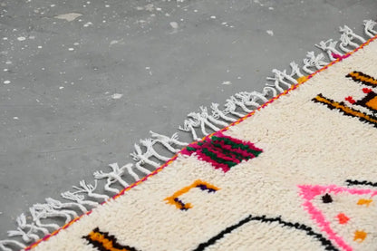 Cream-colored decorbites™ handmade moroccan azilal rug with vibrant geometric patterns and thick white fringe 245x146 cm