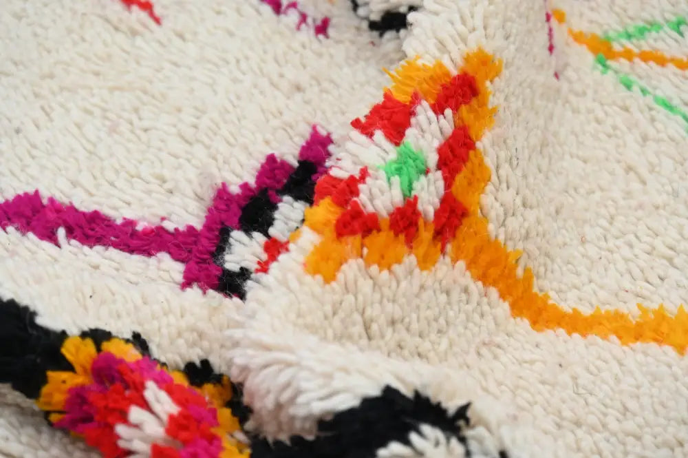 Vibrant handmade moroccan azilal rug with plush white background and bold geometric patterns in magenta orange and black
