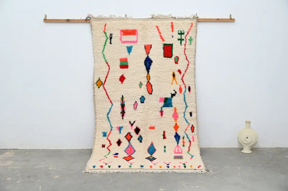 Cream-colored handmade moroccan azilal rug with vibrant pink blue green and red geometric patterns 247x141 cm