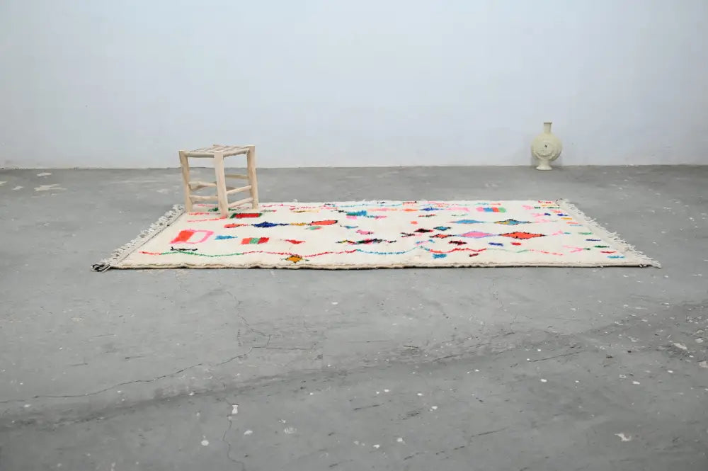 A cream-colored handmade moroccan azilal rug with colorful geometric and abstract patterns by DecorBites™