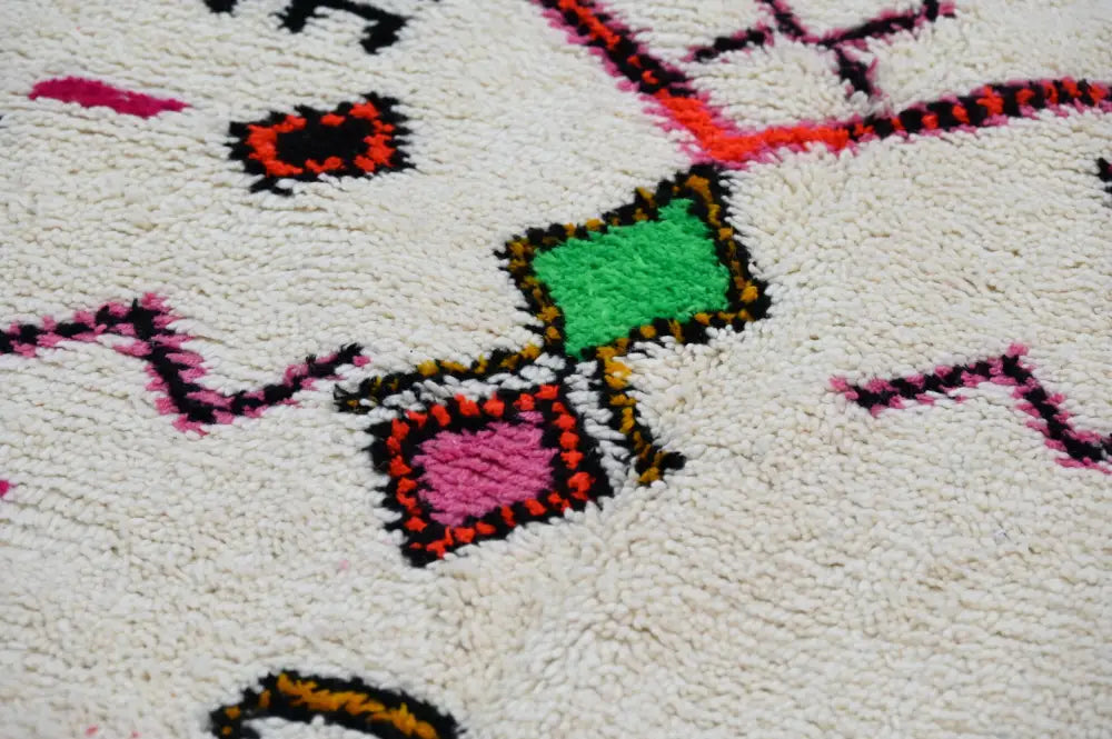 DecorBites™ handmade moroccan azilal rug in white with vibrant green pink and orange geometric patterns and black outlines