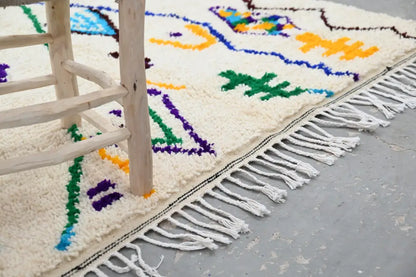 Cream-colored handmade moroccan azilal rug with vibrant blue green yellow purple geometric patterns and fringe edge 250x141 cm