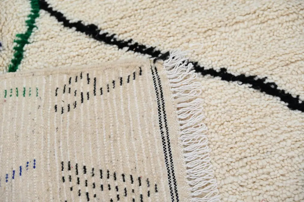 Cream-colored handmade moroccan azilal rug with black green blue geometric patterns and white fringe 250x141 cm
