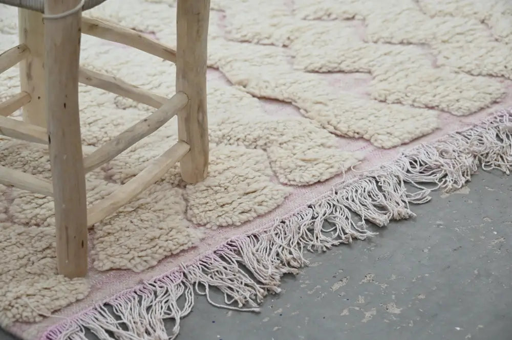 A cream-colored handmade traditional azilal rug with chunky knit texture and delicate pink fringe 250x143cm