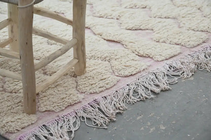 A cream-colored handmade traditional azilal rug with chunky knit texture and delicate pink fringe 250x143cm