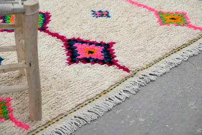 Cream-colored handmade moroccan azilal rug with vibrant pink green and blue geometric patterns and white fringe 250x148 cm