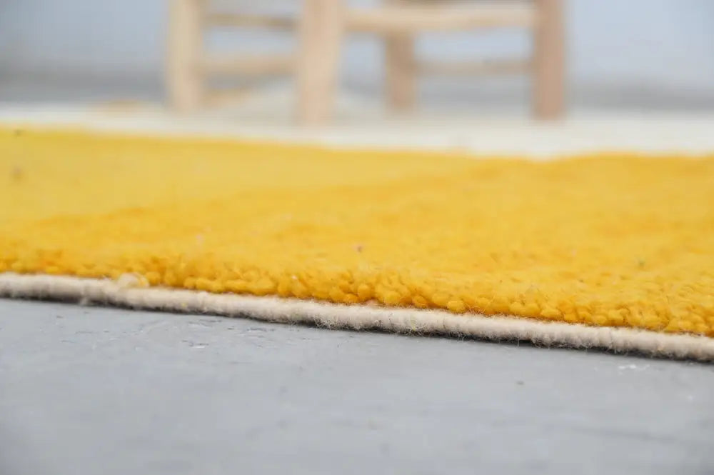 A vibrant yellow decorbites™ handmade traditional moroccan azilal rug 250x149 cm with soft textured surface and white border