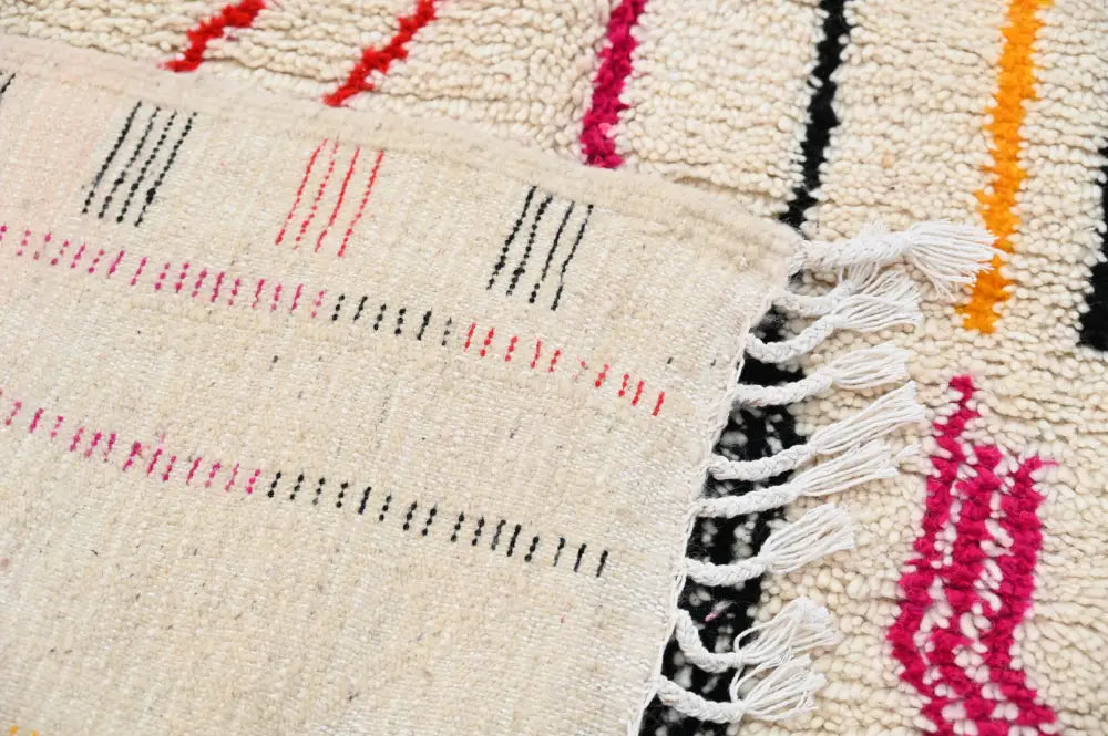 Beige handmade traditional azilal rug with vibrant red black and orange geometric patterns and white fringe 253x144 cm