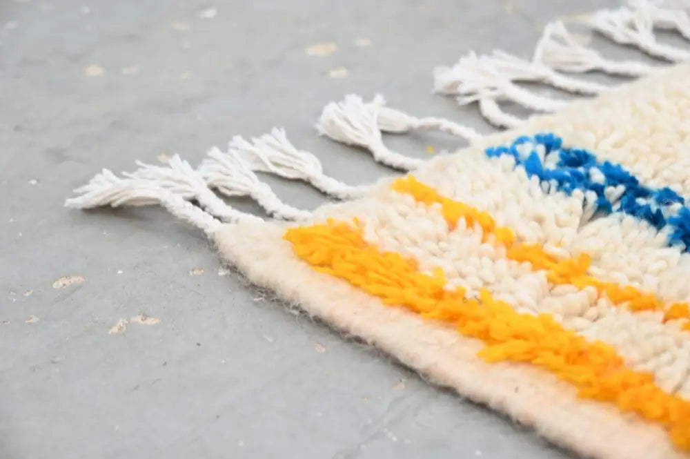 DecorBites™ handmade traditional Azilal rug with bold cream orange and deep blue wool stripes and white yarn fringe