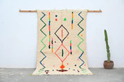 Beige moroccan azilal rug with colorful geometric patterns in red green blue orange made of natural wool 253x150 cm